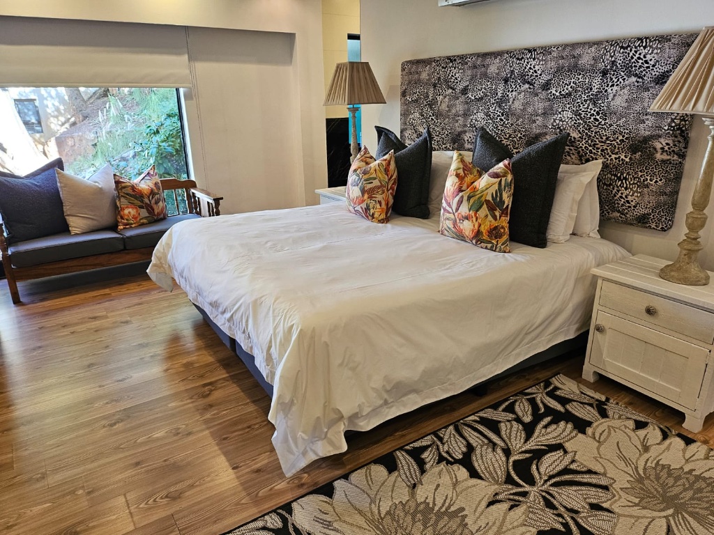 King bed with leopard print headboard, floral cushions and wooden floors