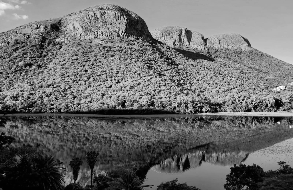 Panoramic view of Hartbeespoort Dam at golden hour with Magaliesberg mountains reflected in still water