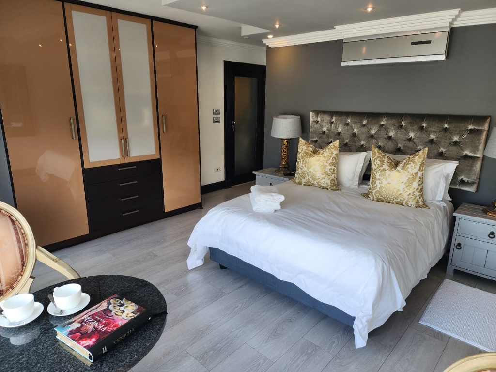 Luxury bedroom with velvet tufted headboard, gold cushions and elegant lamps
