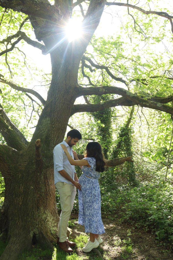 Couple under sunlit tree maternity