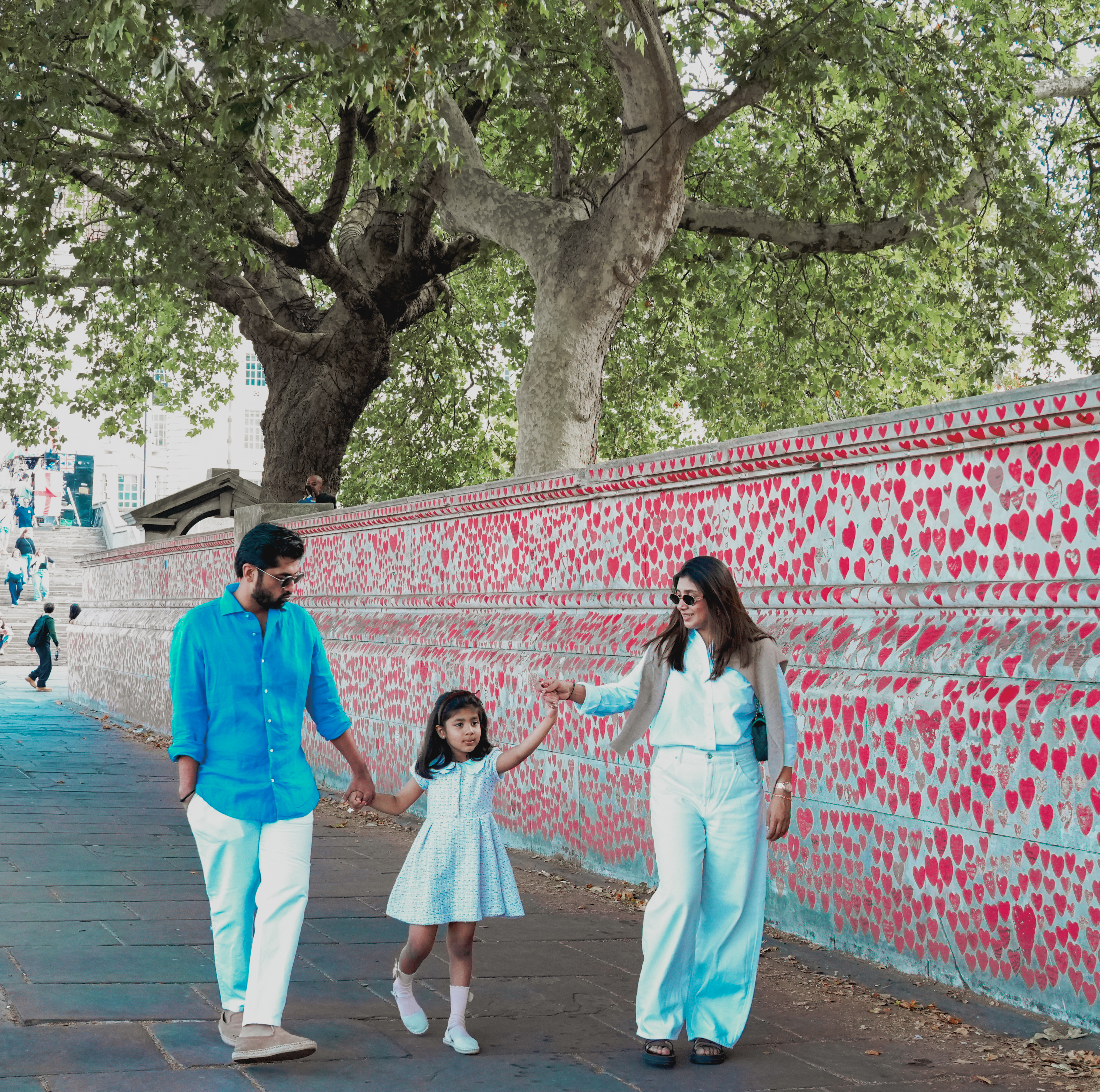 Family walking along path by wall covered in painted hearts