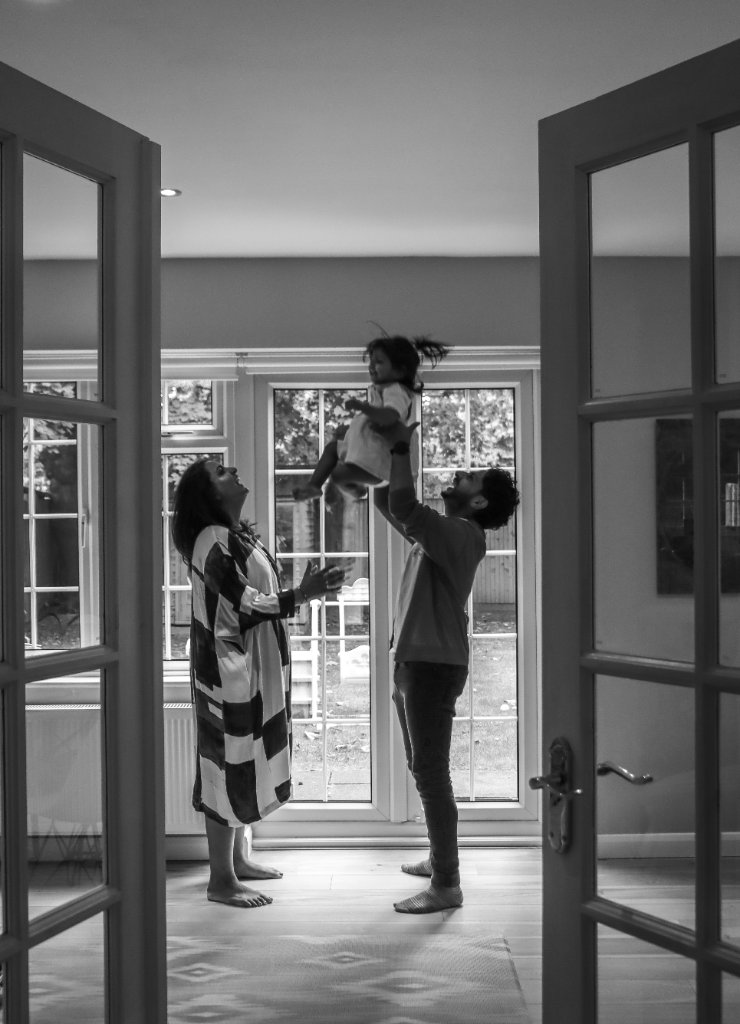 Father lifting child in black and white through french doors