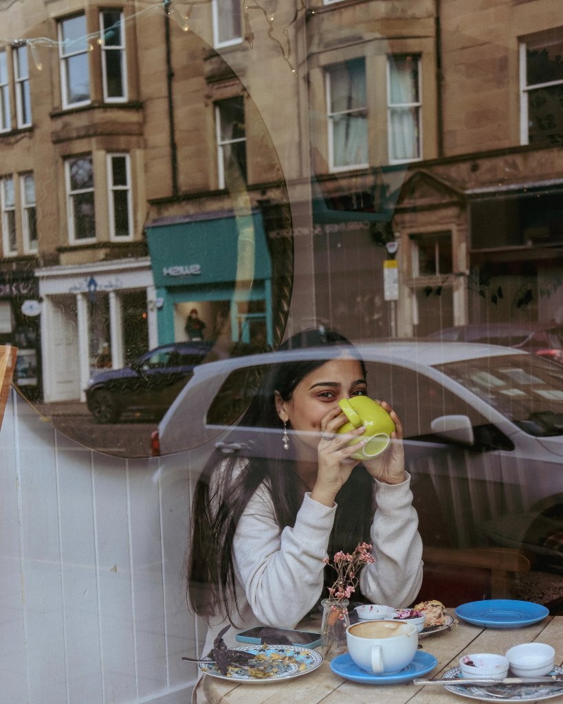 Portrait of woman drinking coffee by cafe window