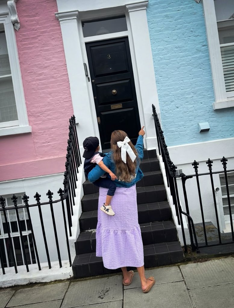 Pregnant woman on steps by colorful pink and blue door