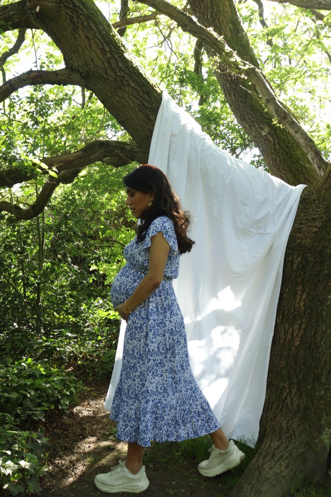 Pregnant woman by white fabric in woodland