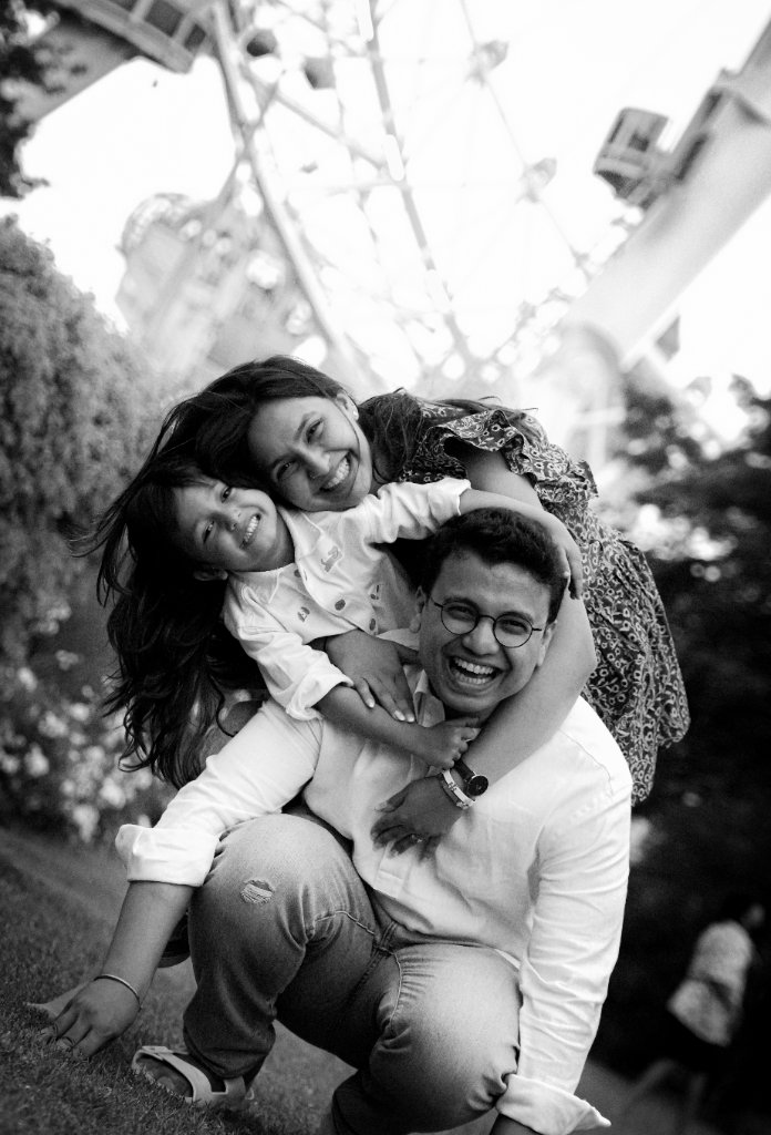 Black and white family laughing with child on shoulders