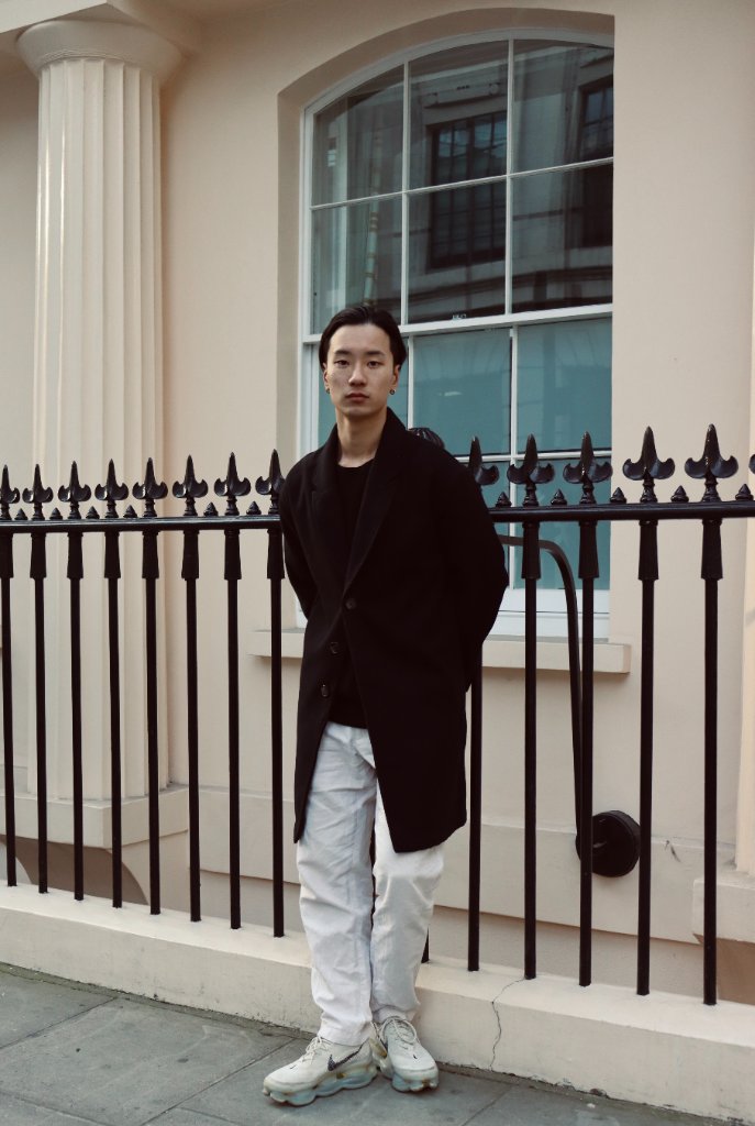 Street portrait of man in black coat by iron railings