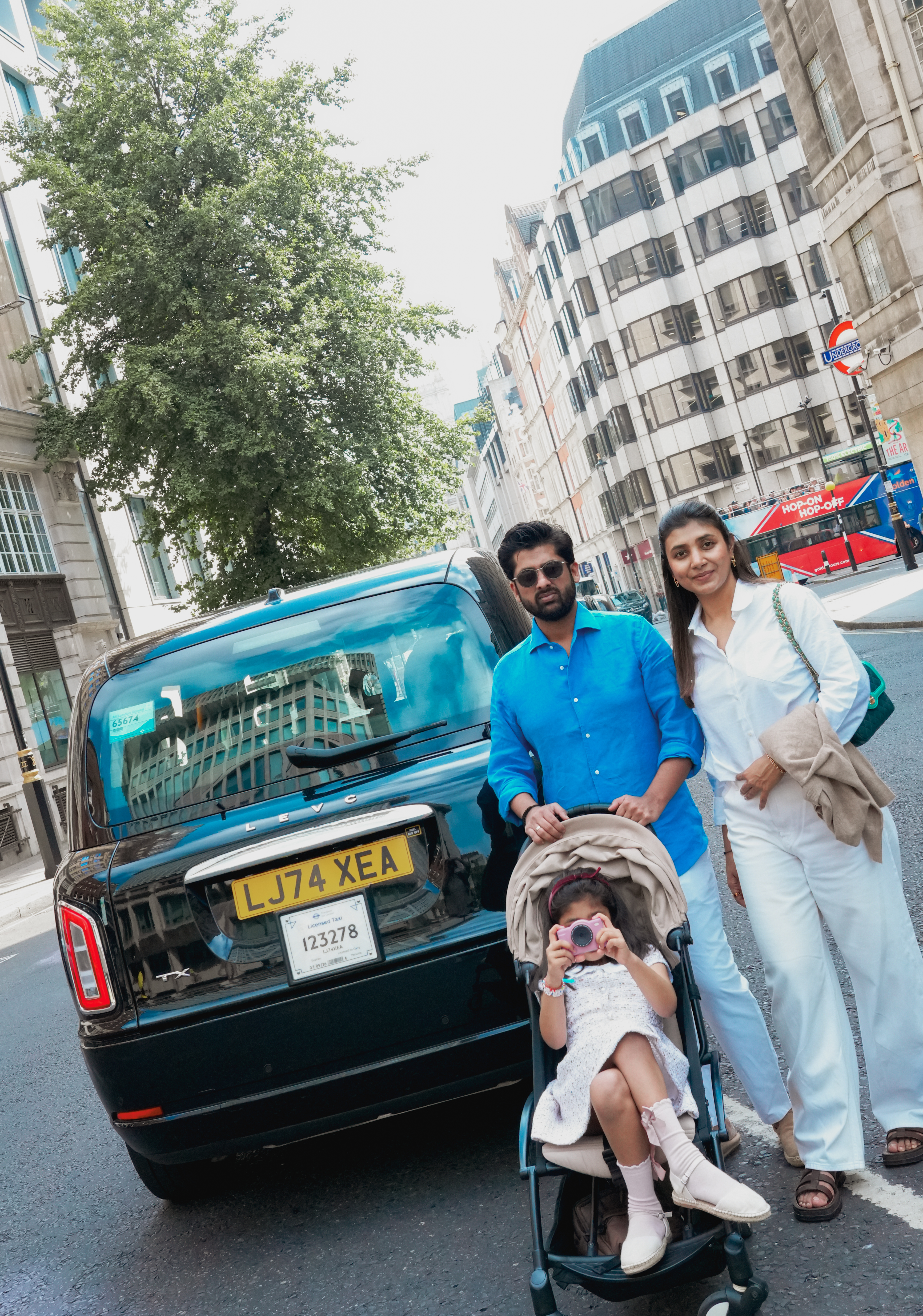 Family beside black London taxi with daughter in stroller