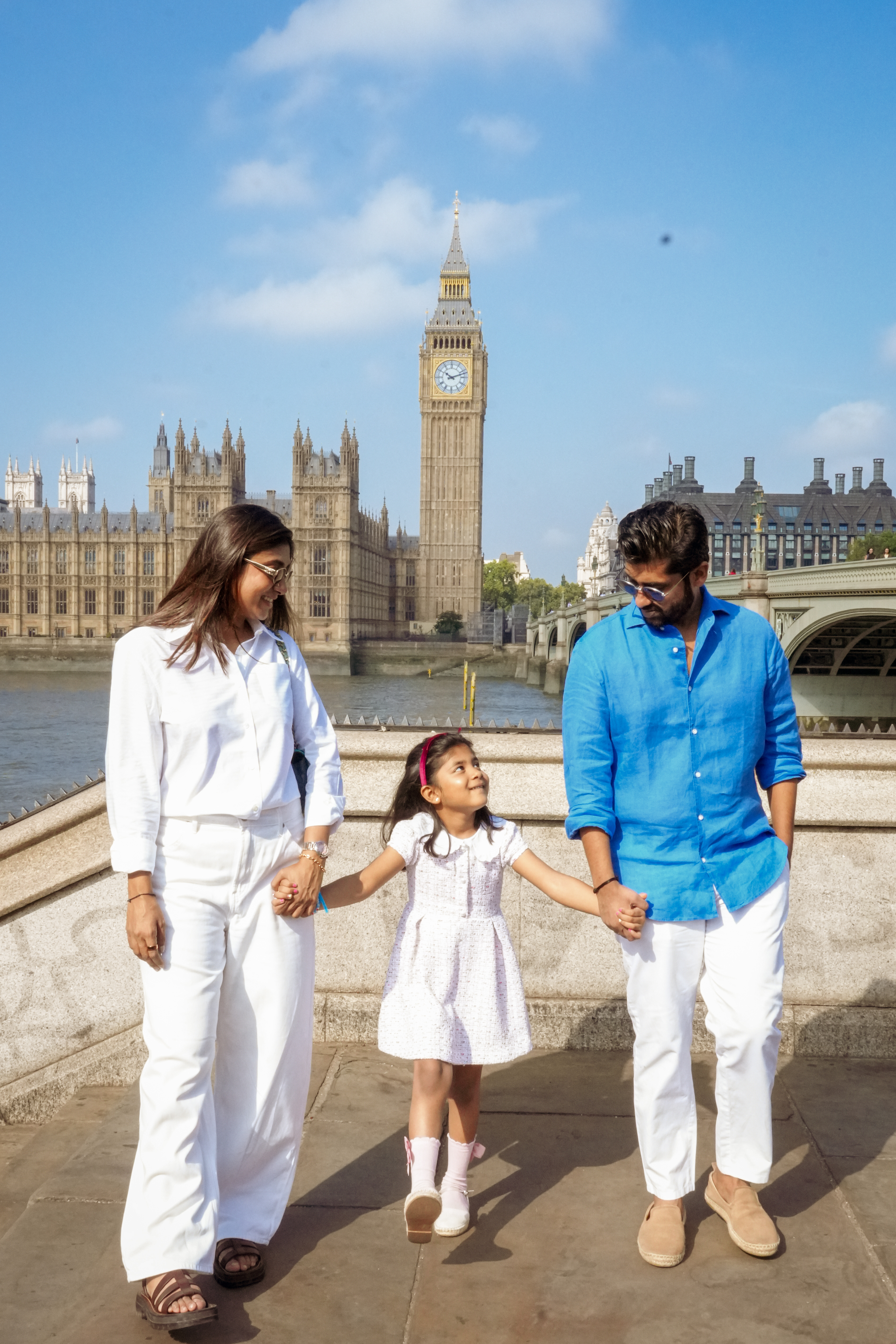 Family walking hand in hand along Thames embankment with Big Ben behind