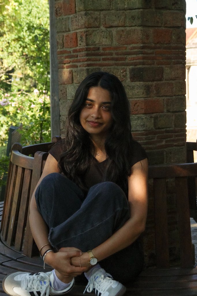 Portrait of woman sitting on bench by brick column in garden
