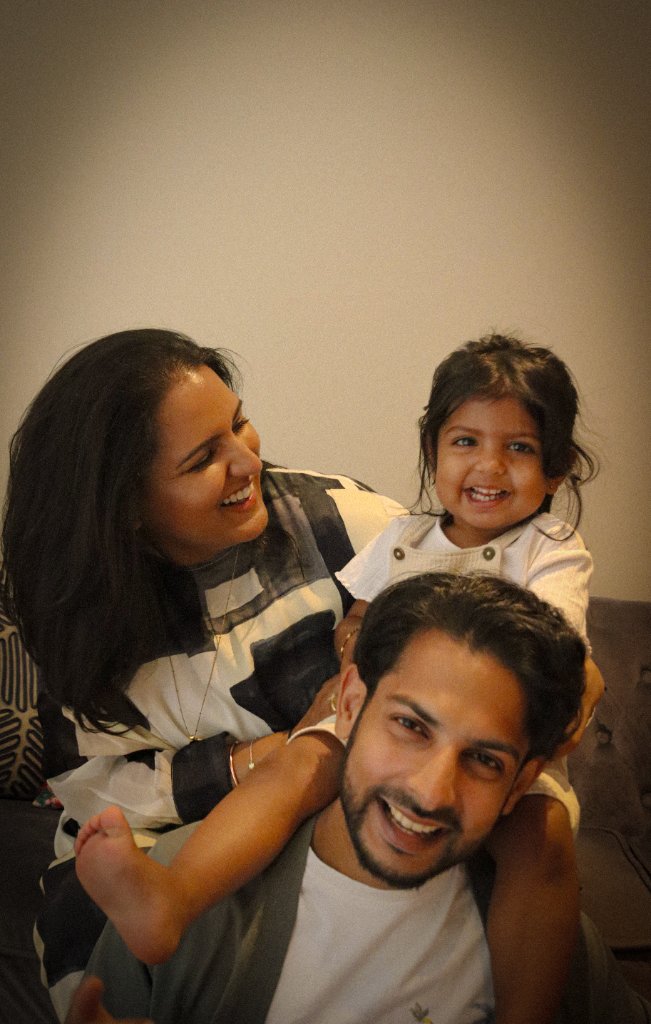 Family laughing together with toddler on shoulders