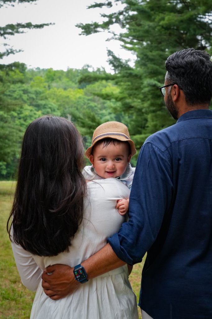 Family of three in forest with baby looking at camera
