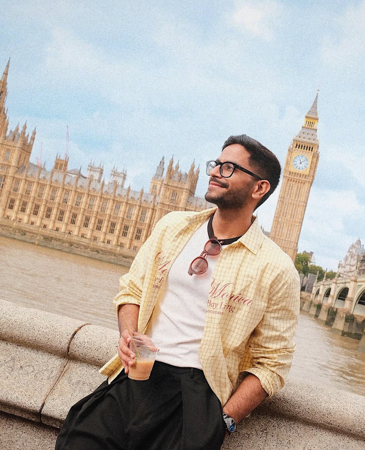 Portrait of young man in yellow check shirt leaning on Westminster Bridge