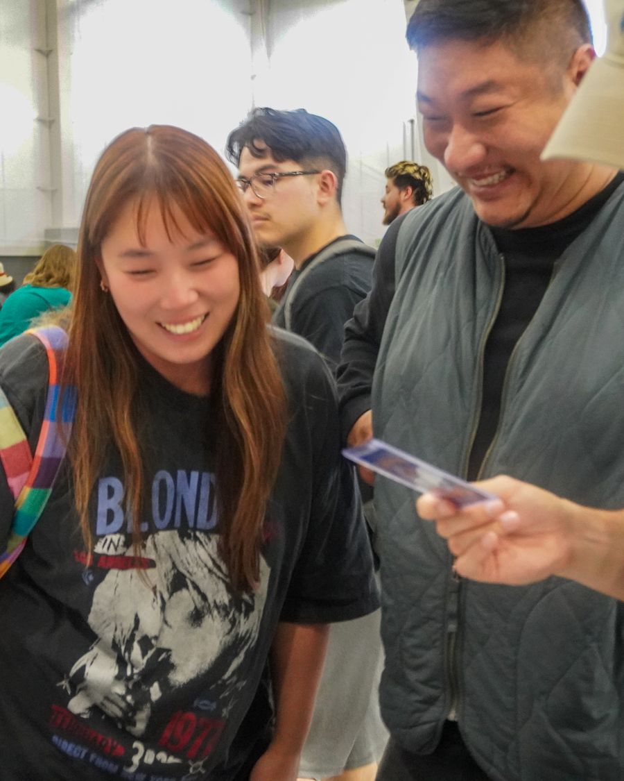 Collectors smiling over a card at the CardFellas booth