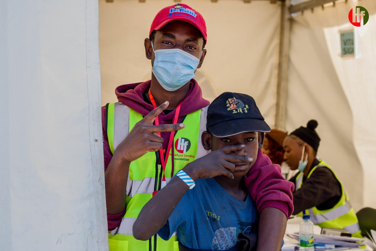 A volunteer and a young boy posing together at a community care event