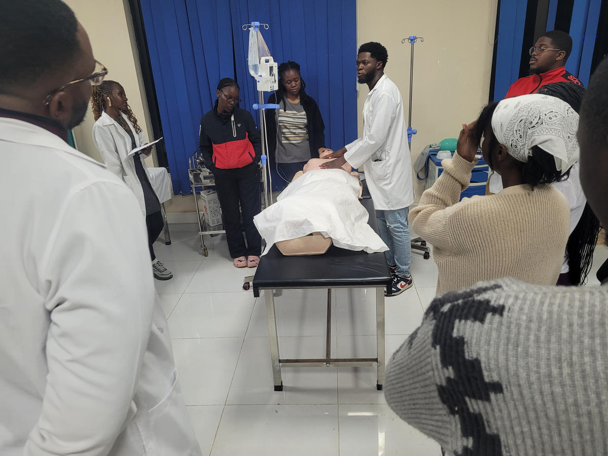 Medical students observing a clinical training simulation on a mannequin