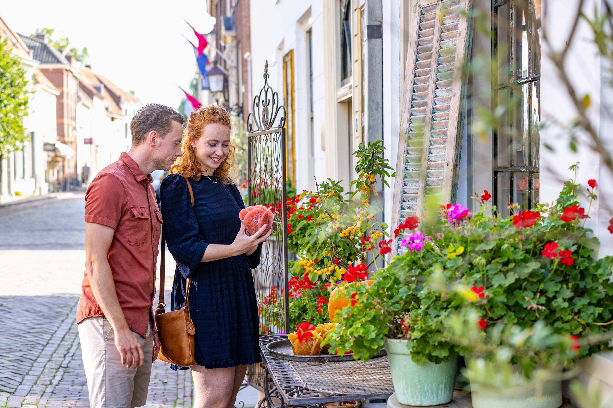 Bezoekers bekijken informatie tussen historische Burense panden en bloemen