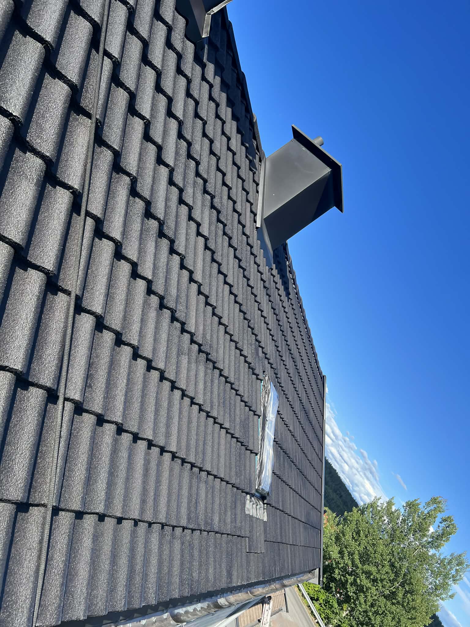 Mørkt tegltak med skorstein og takvindu