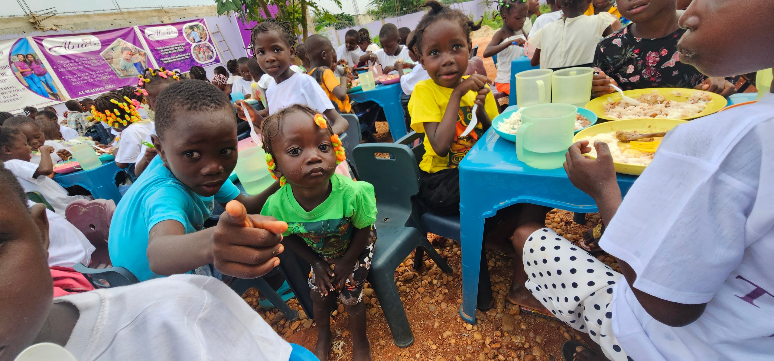Niños comiendo en mesas de Alma ONG en Angola