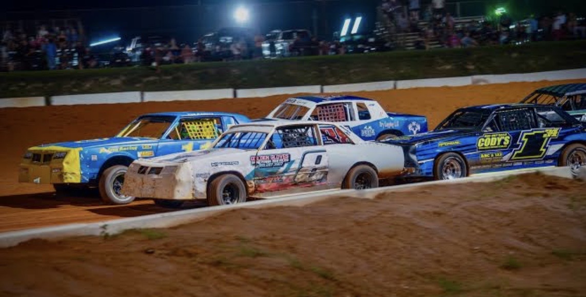 Bomber class dirt track race cars racing at night on clay