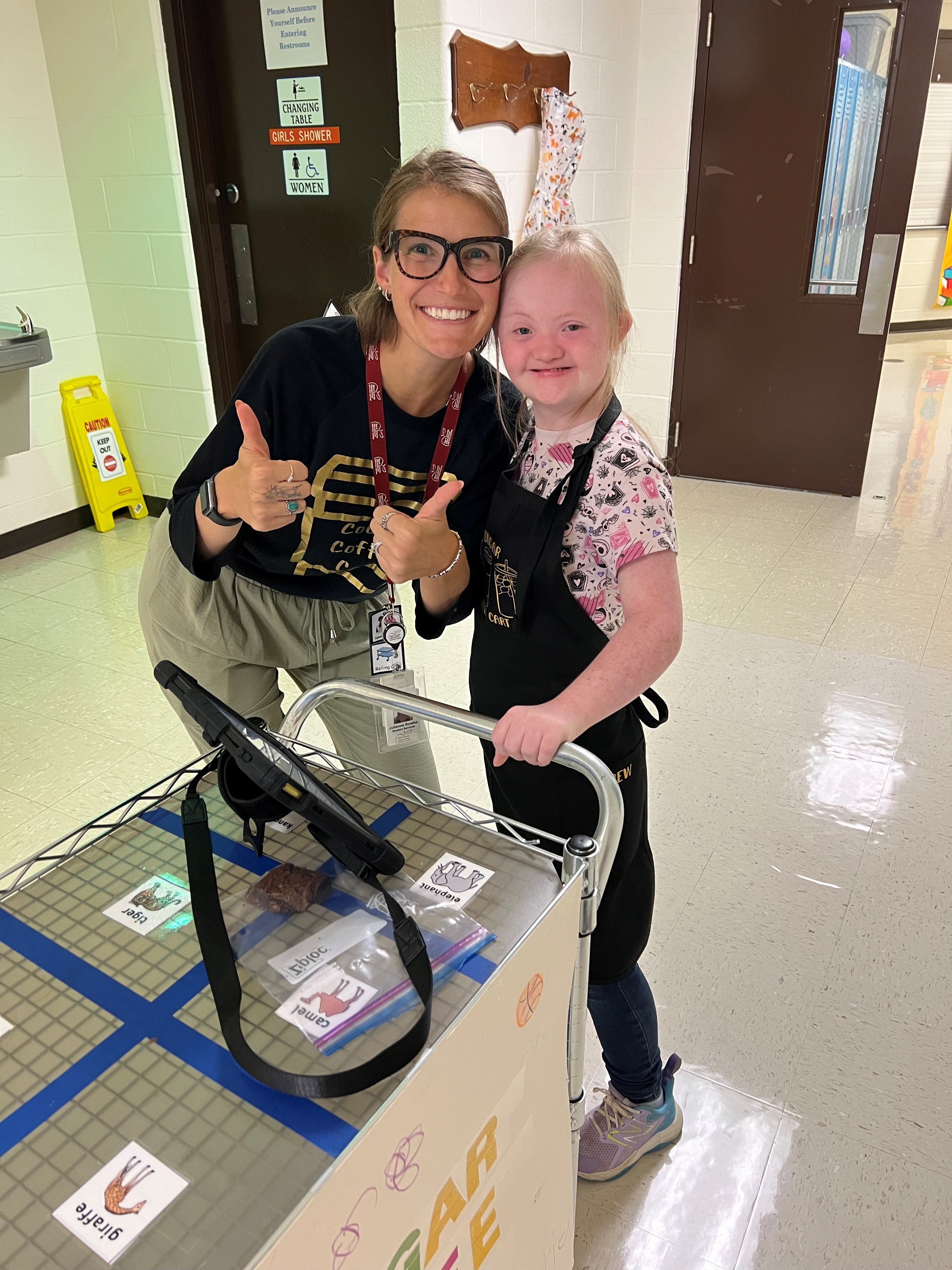 Staff member and a smiling child in a school hallway