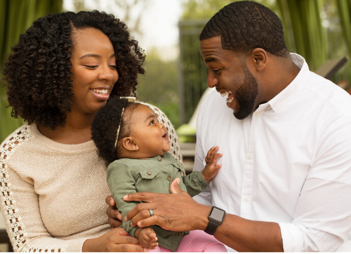 Young family with baby smiling outdoors