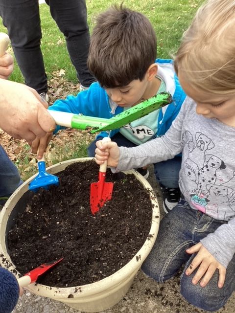 Young children planting in a flower pot in a Head Start garden activity