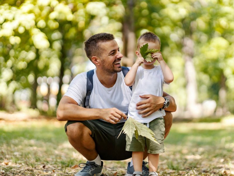 Father crouching with his toddler in a park
