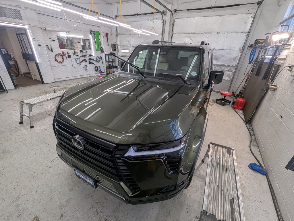 Dark olive green Lexus SUV in detail shop