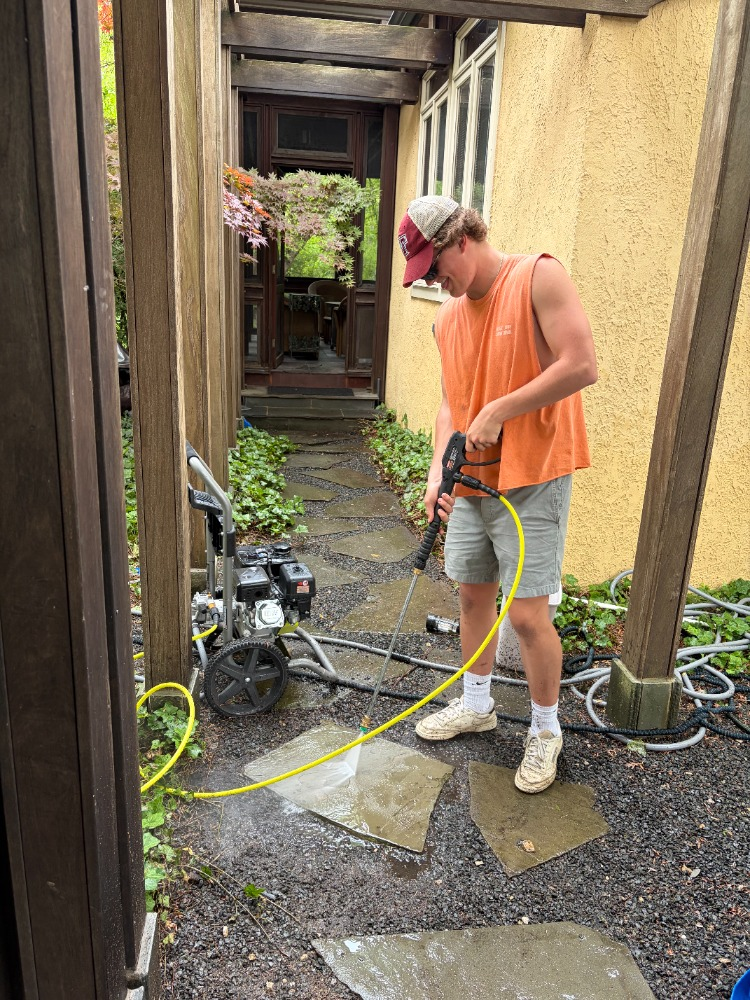 Teo power washing a stone patio walkway at a residential property