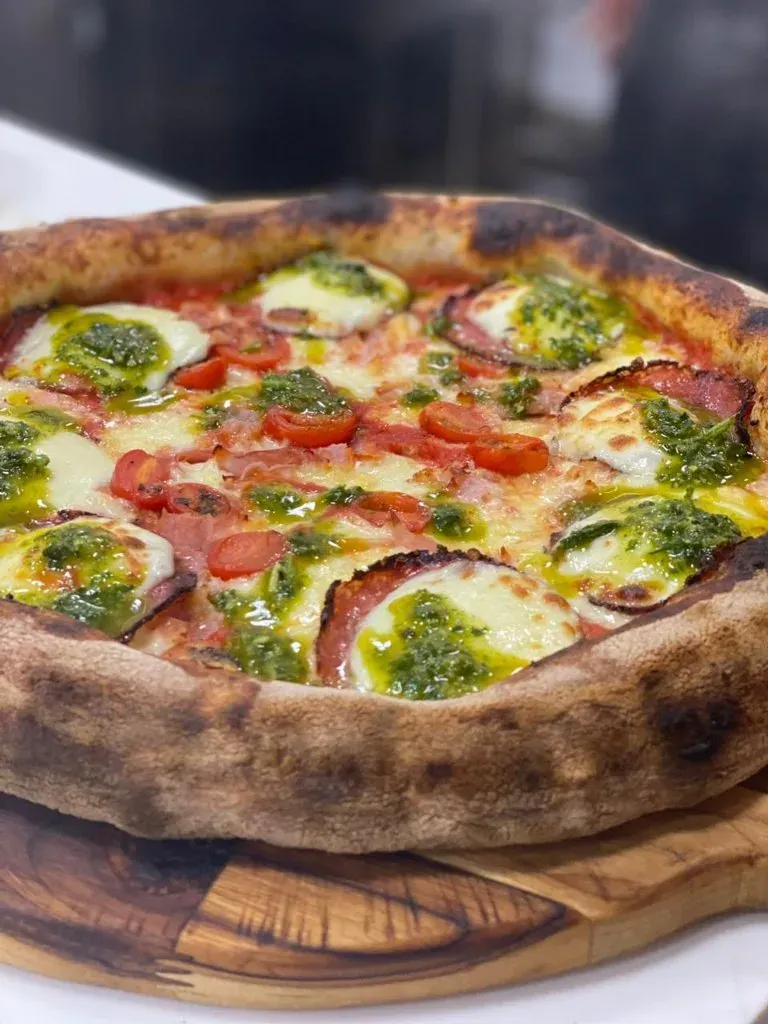 Pizza pronta com tomate, queijo e pesto, da Varanda 228.