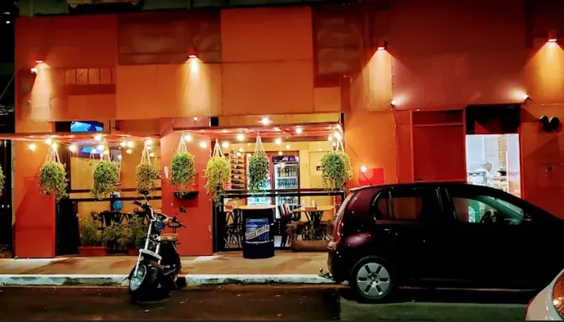 Fachada da Varanda 228 na Vila Romana, com mesas na entrada e iluminação noturna.