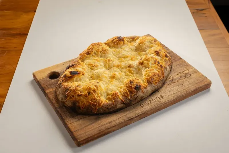 Crostini de massa de pizza com parmesão sobre tábua, da Varanda 228.