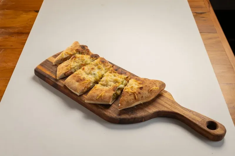Calzone di Mare servido em pedaços sobre tábua, da Varanda 228.