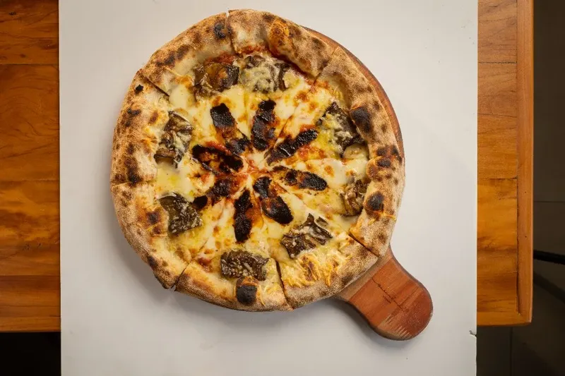 Pizza Varanda 228 com berinjela confitada, queijo maasdam e creme de alho negro.
