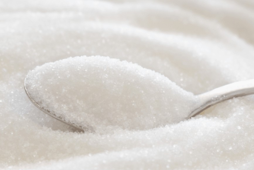White sugar crystals close-up with spoon