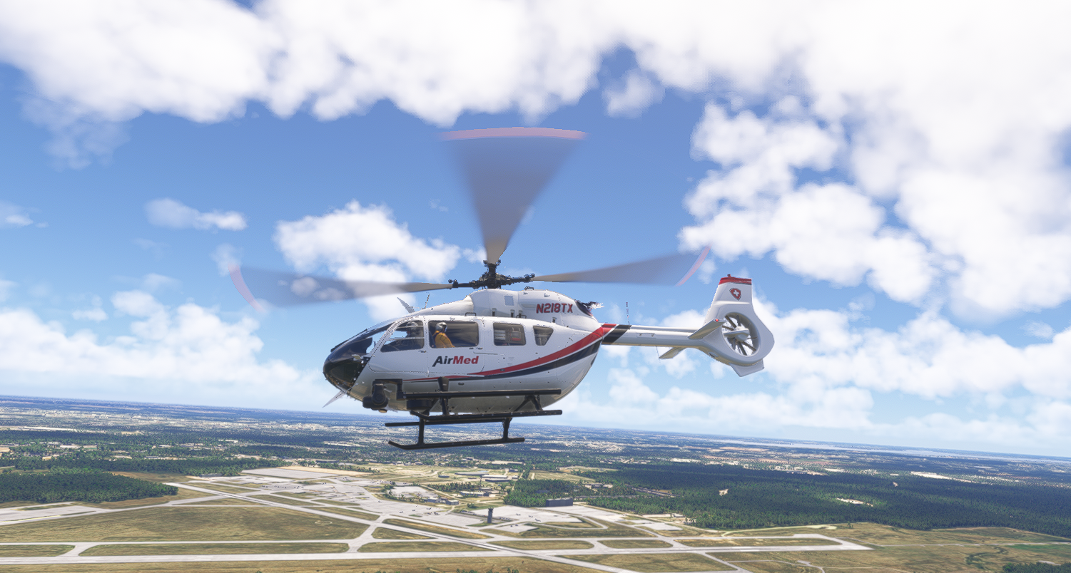 AirMed helicopter (N218TX) in flight over an airport complex