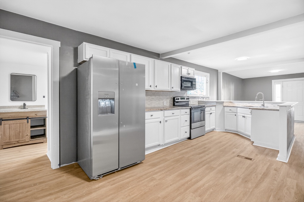 Bright Kitchen with White Cabinetry and Marble Peninsula Counters