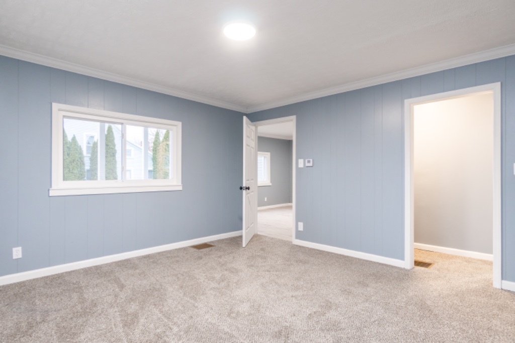 Spacious Bedroom with Soft Blue Paneling and Neutral Carpeting