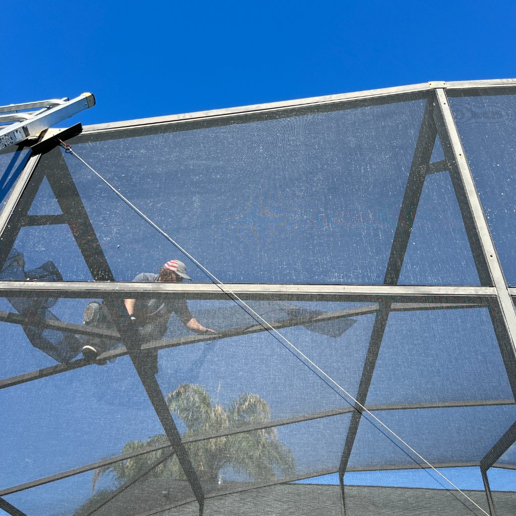 Screen repair technician working on pool cage roof panels