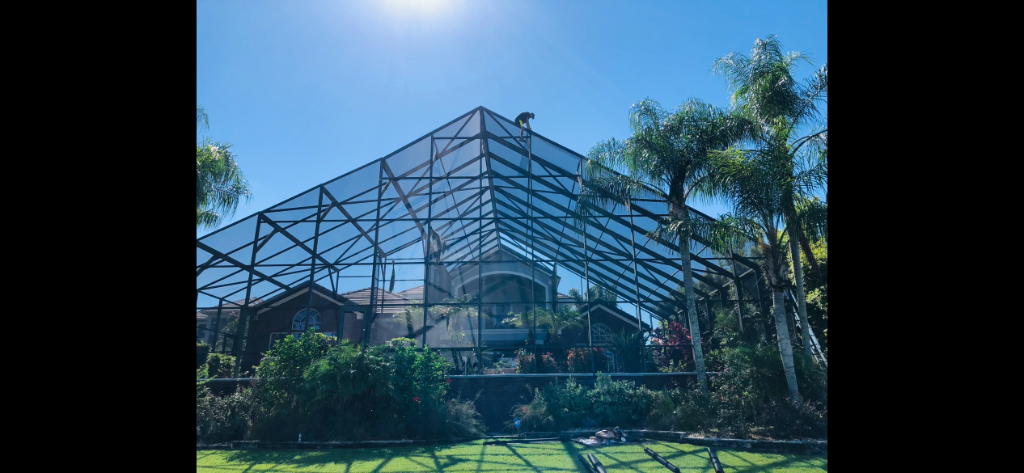 Pool screen repair technician replacing roof panels on large two story enclosure