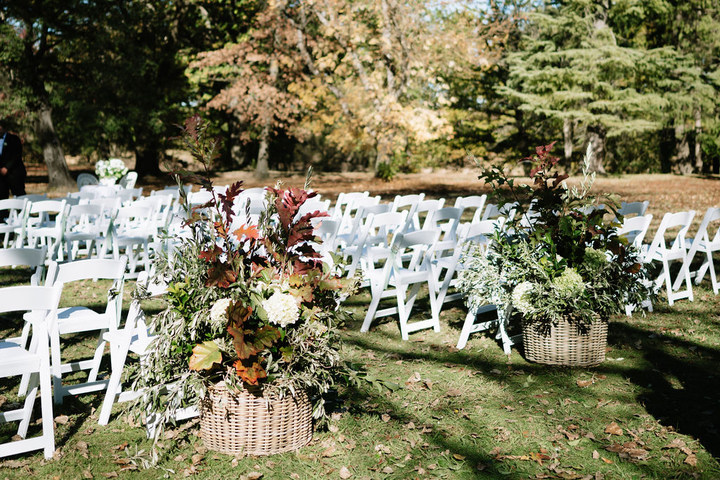 Outdoor wedding ceremony setup with floral arrangements and white chairs