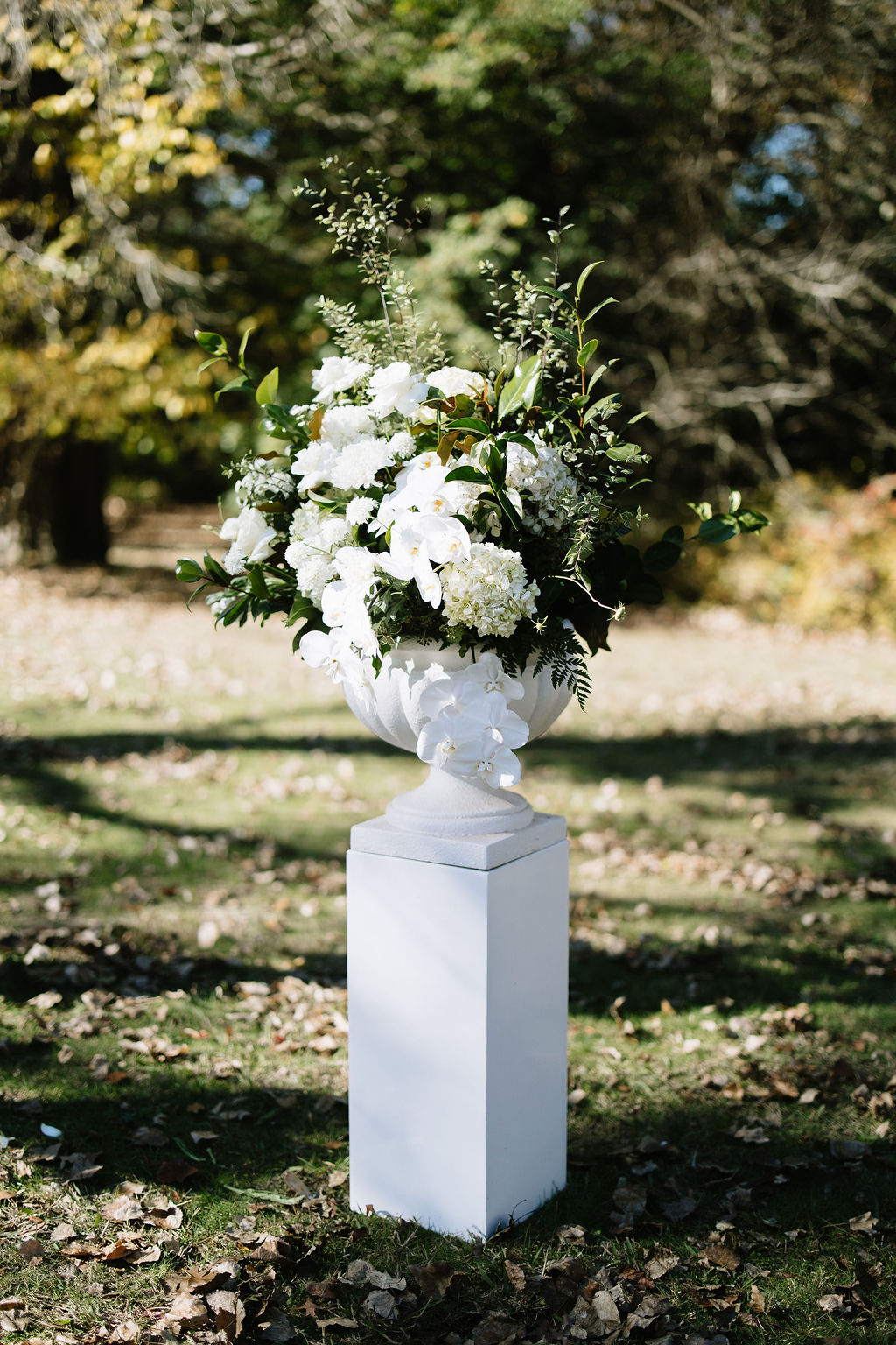 White floral arrangement on pedestal — tutto events