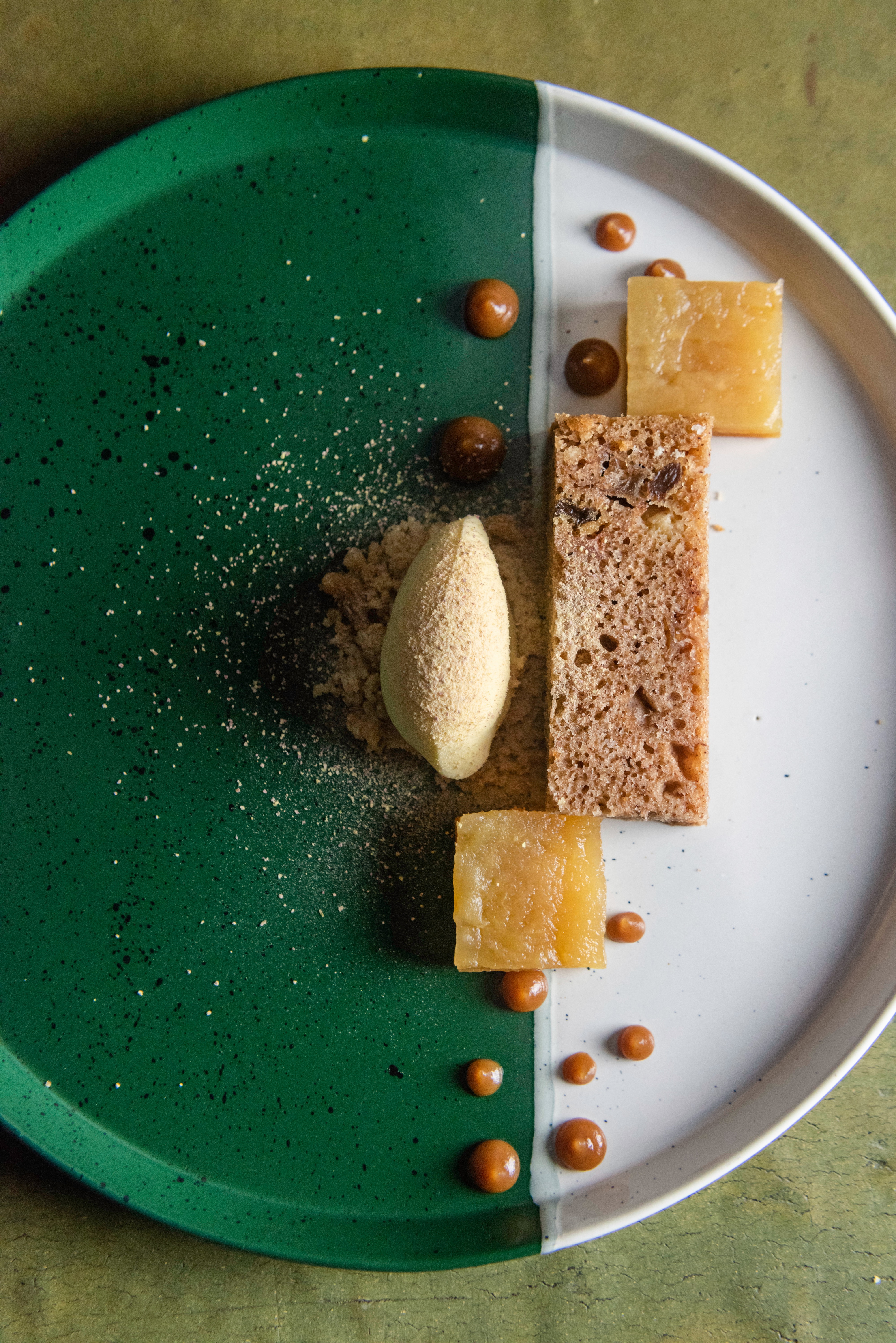 An artfully plated dessert on a green-and-white plate