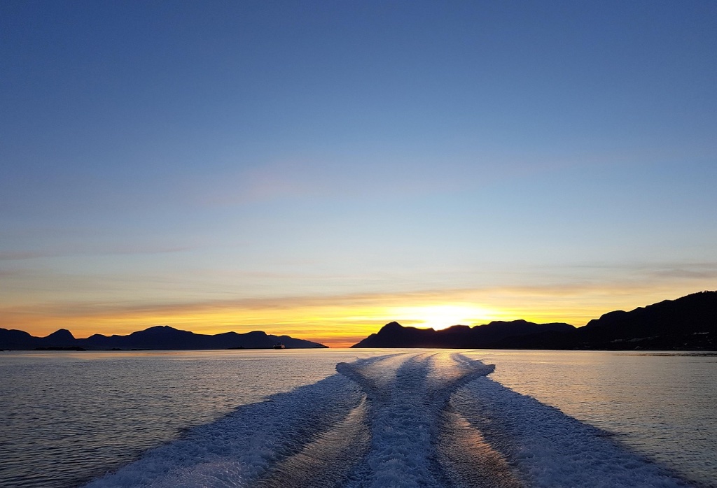Plavba při západu slunce mezi norskými fjordy