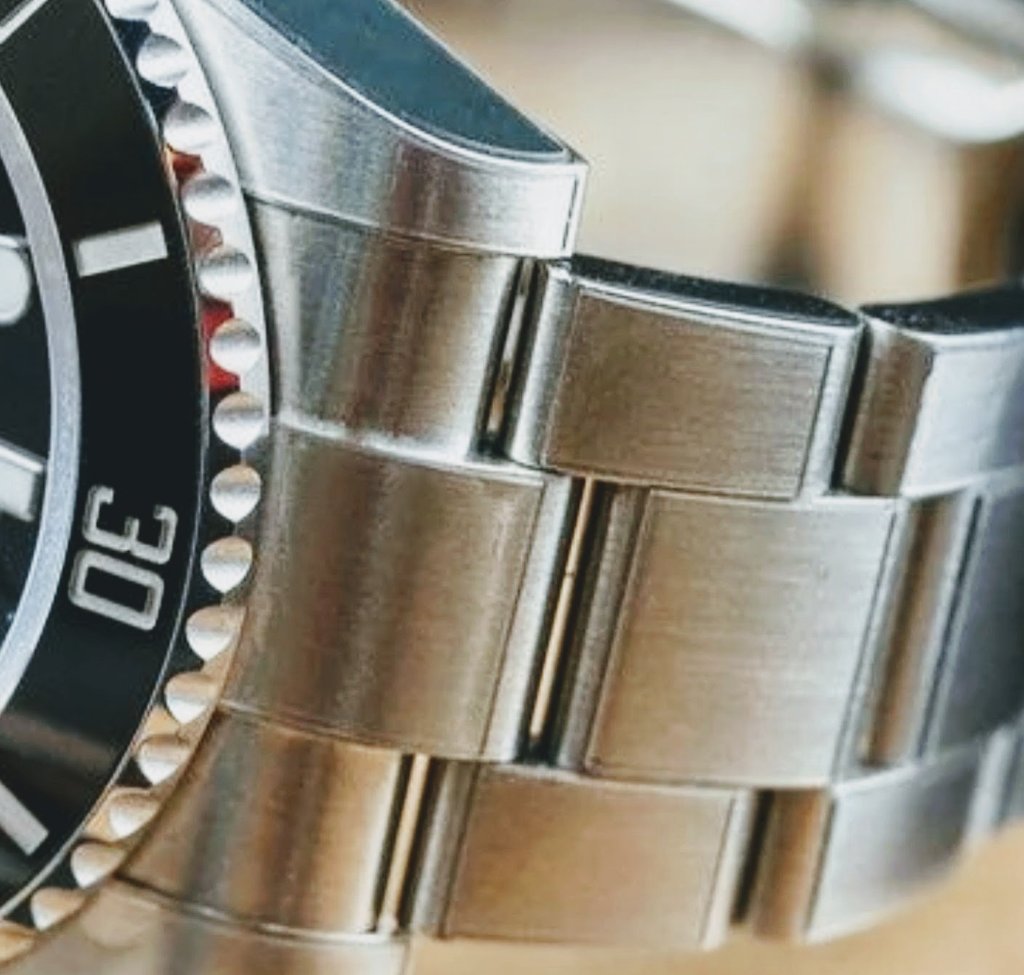 Side profile of a stainless steel luxury watch showing brushed bracelet links and polished lugs