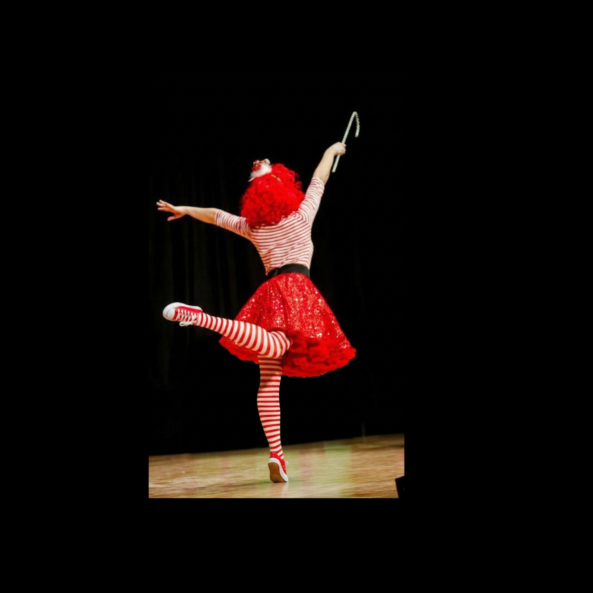 Performer in a candy cane dance pose on stage