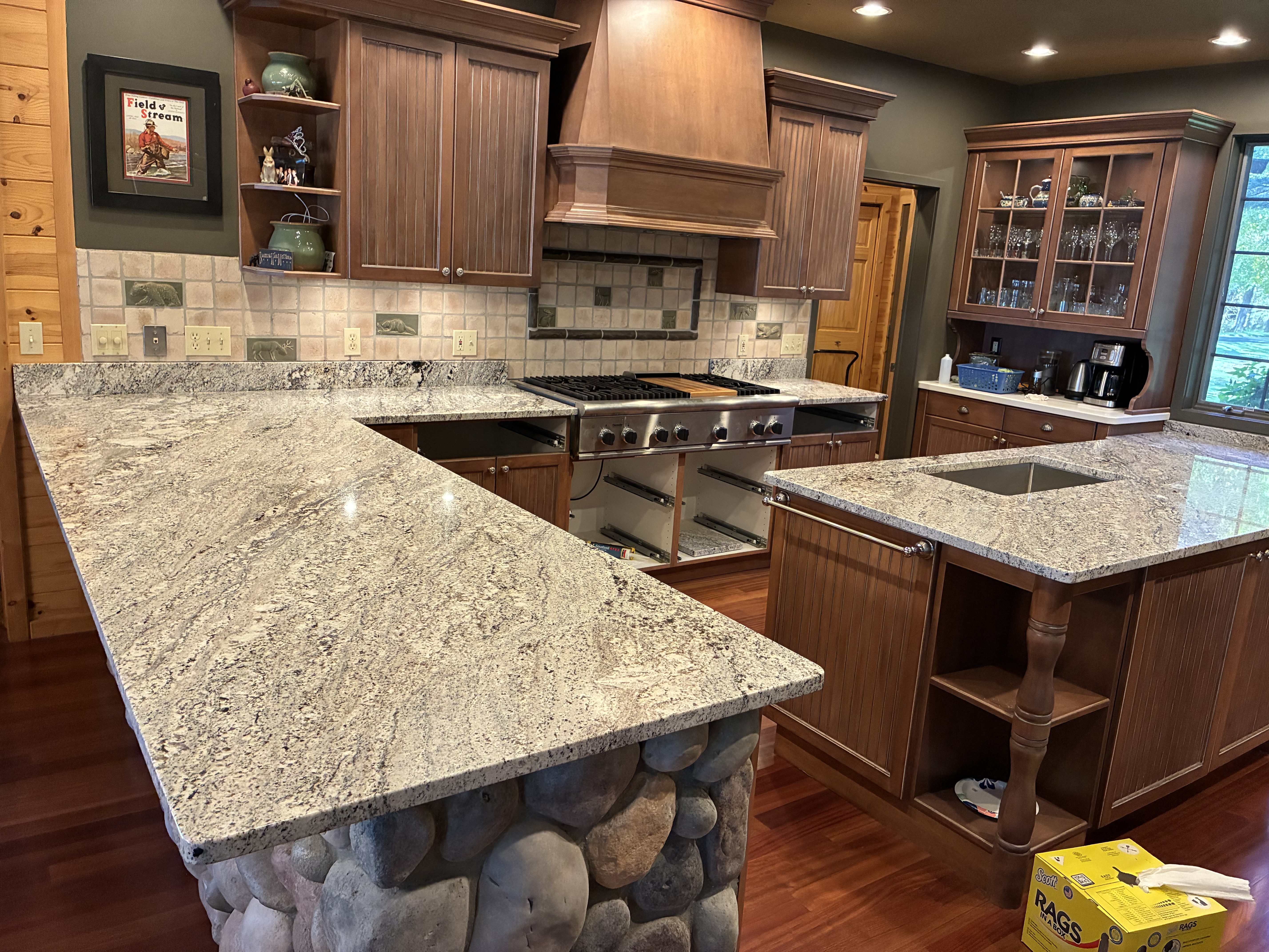 Rustic kitchen with light granite countertops and river stone peninsula base
