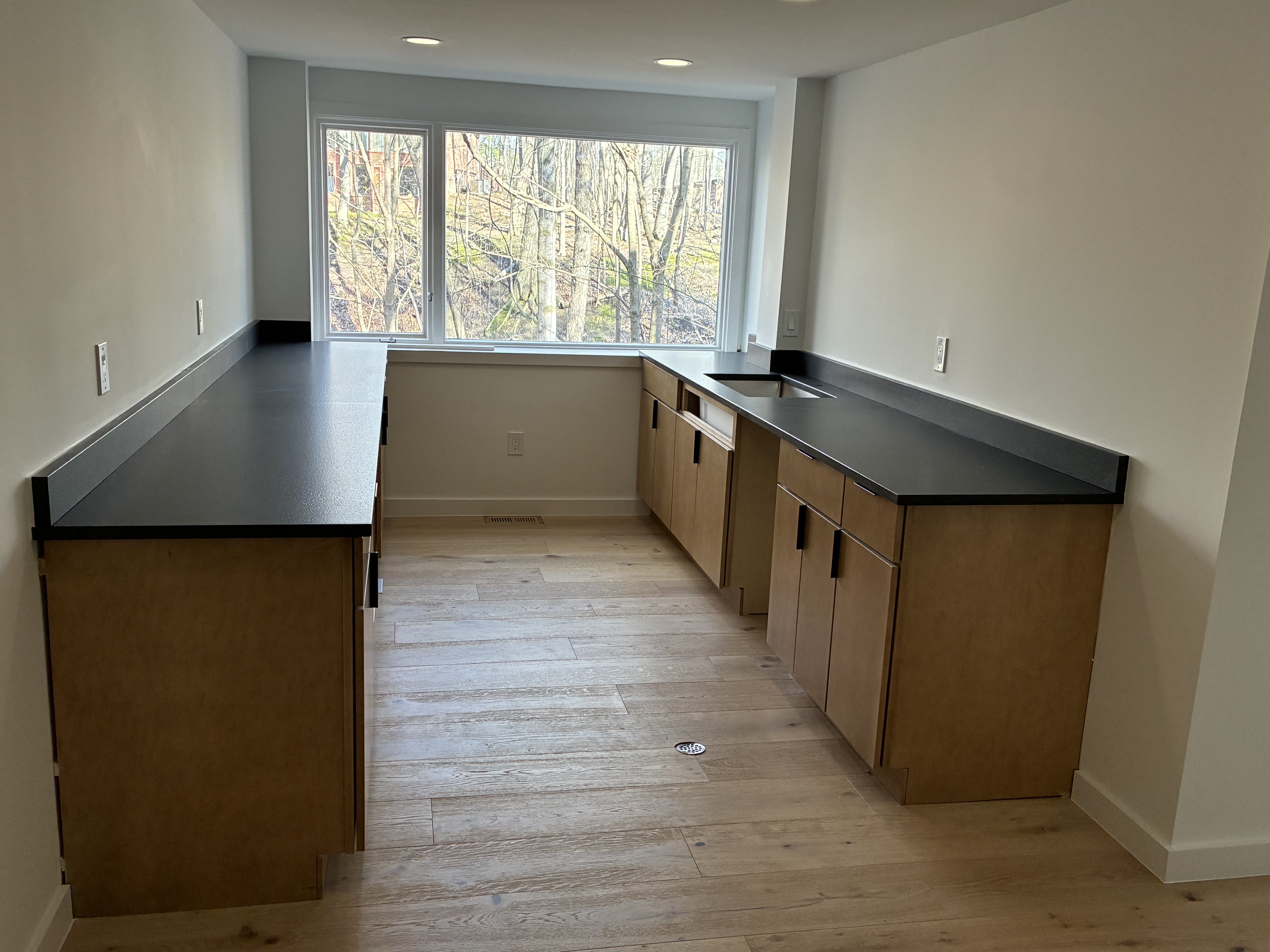 L-shaped kitchen with black countertops and natural oak cabinets