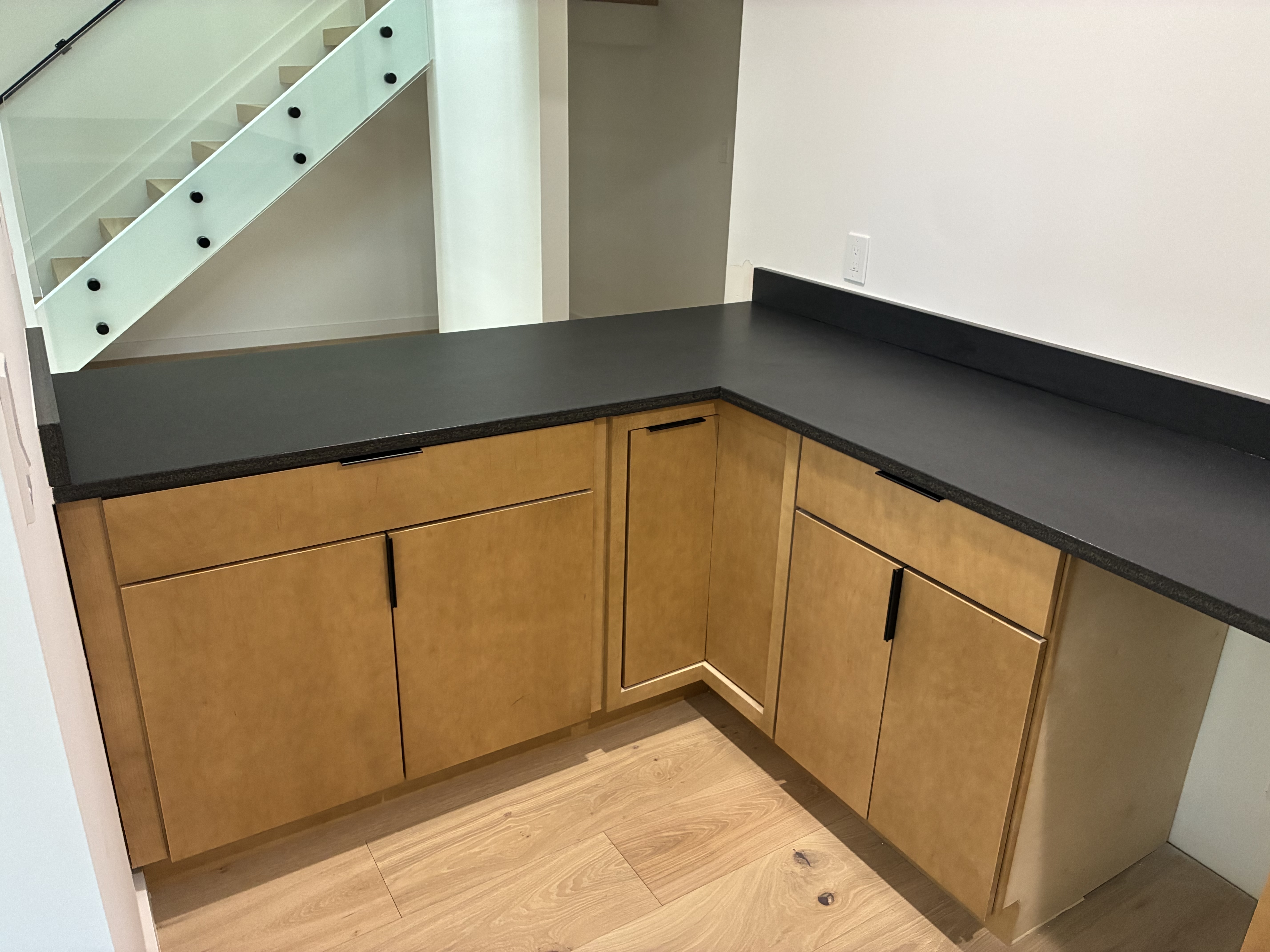 L-shaped kitchen island with black countertop and warm wood cabinetry